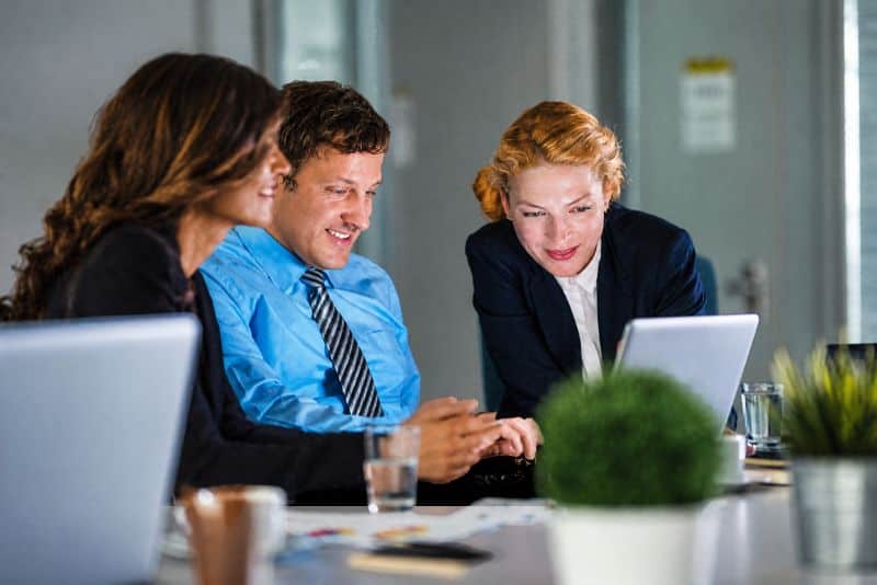Customer-Collaboration-Microsoft-365 Team of business professionals collaborating on laptops in a meeting.