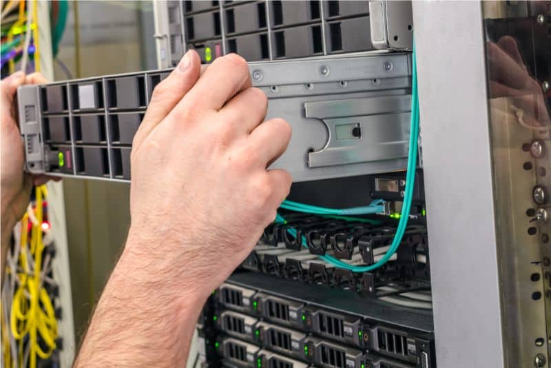 Server-Installation Technician hand installing or adjusting server rack in data center.